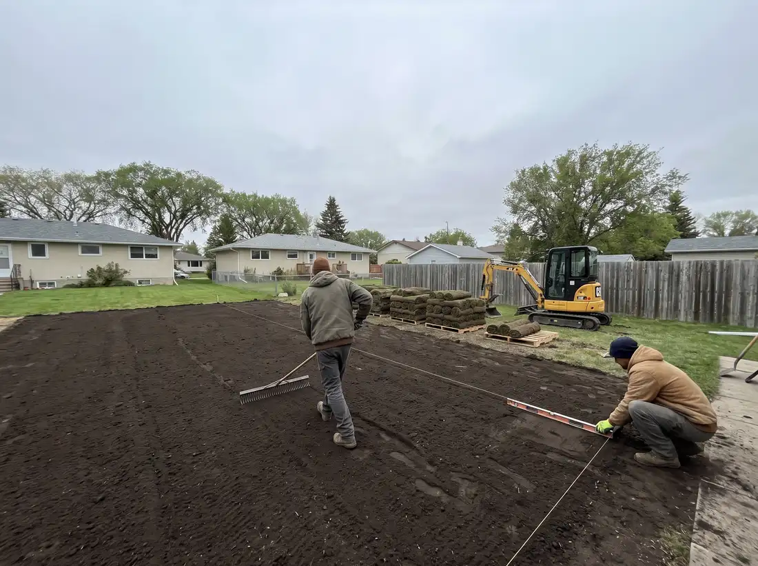 A landscaping crew grading and preparing a residential yard in Saskatoon, SK